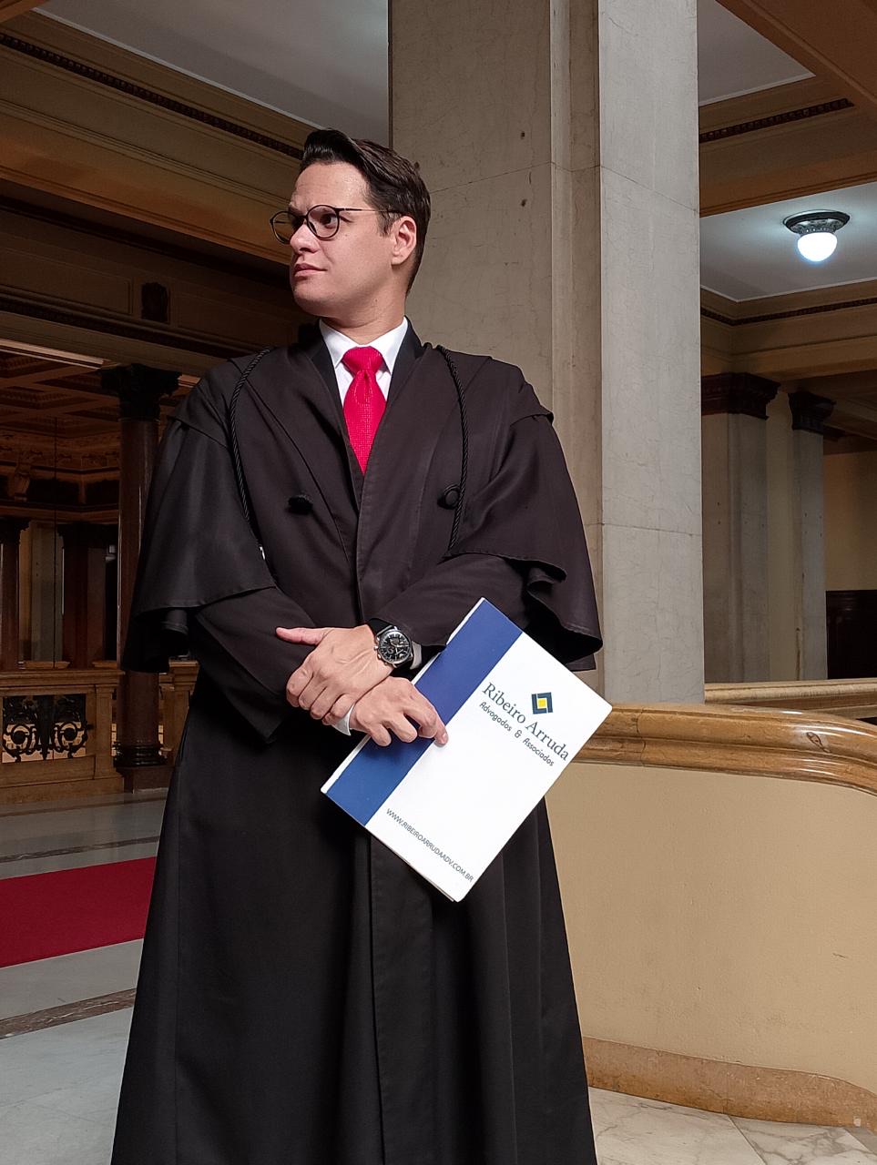 Lucas Ribeiro Arruda em traje profissional com pasta do escritório